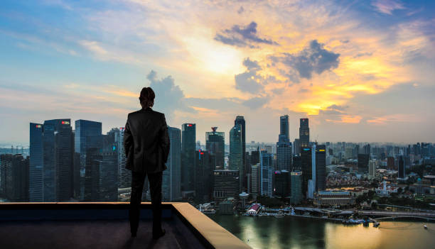 Businessman Watching The City On The Rooftop Of Skyscraper